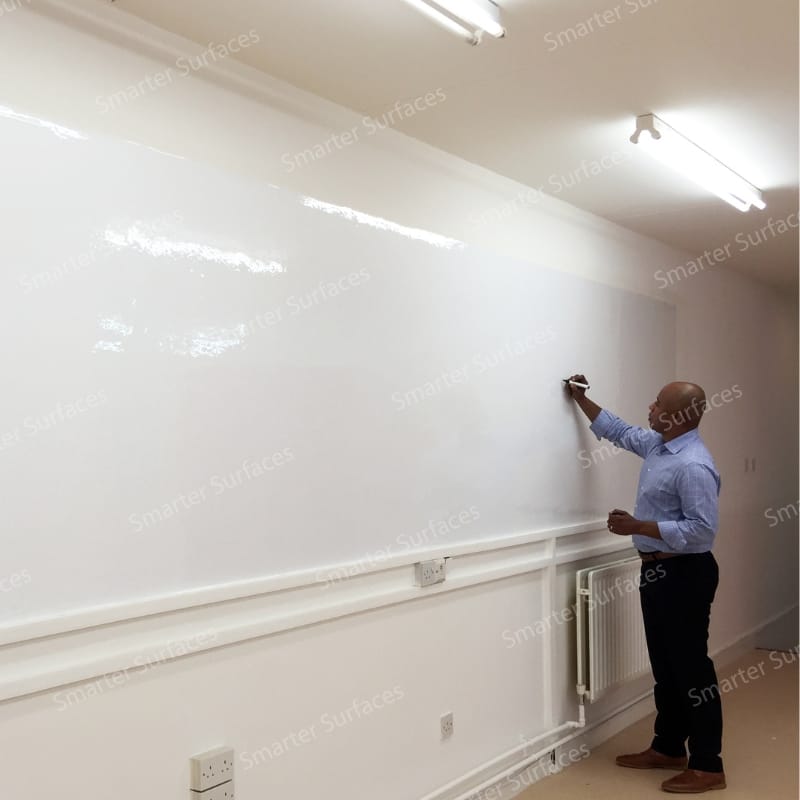 Person in blue shirt writing on large best dry erase wallpaper- covering entire wall in classroom or office