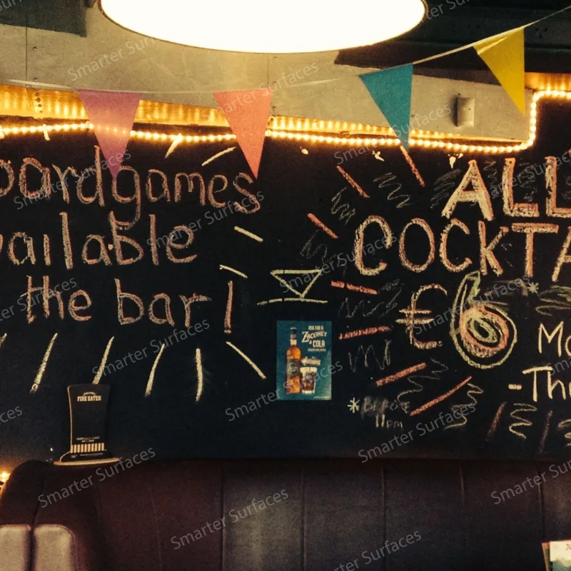 Chalkboard paint menu wall inside a bar with hand-drawn cocktails and messages