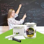 A teacher writing on a black chalkboard during class