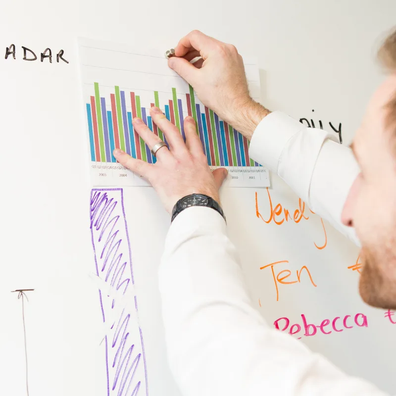 Children's colorful drawings and artwork displayed on white magnetic dry erase board wall.