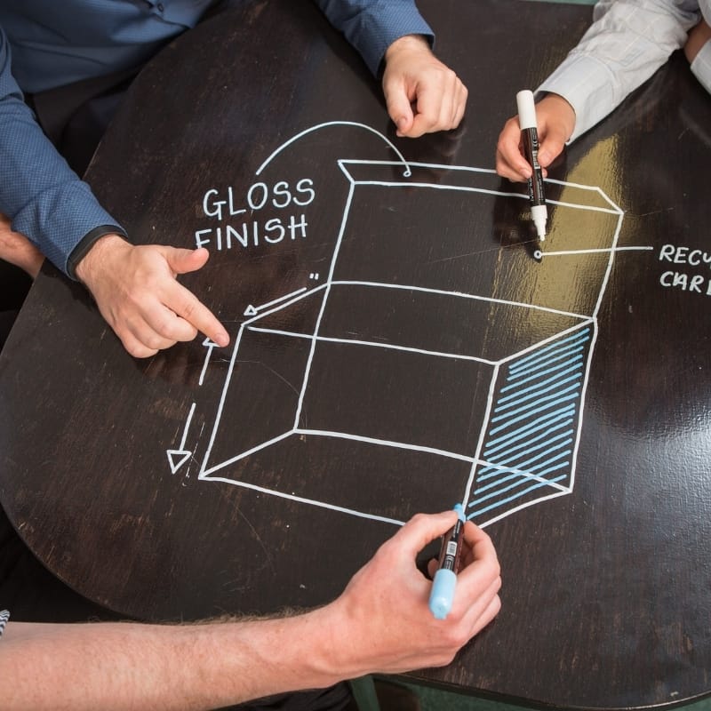 People drawing a technical design on a surface covered with clear whiteboard film