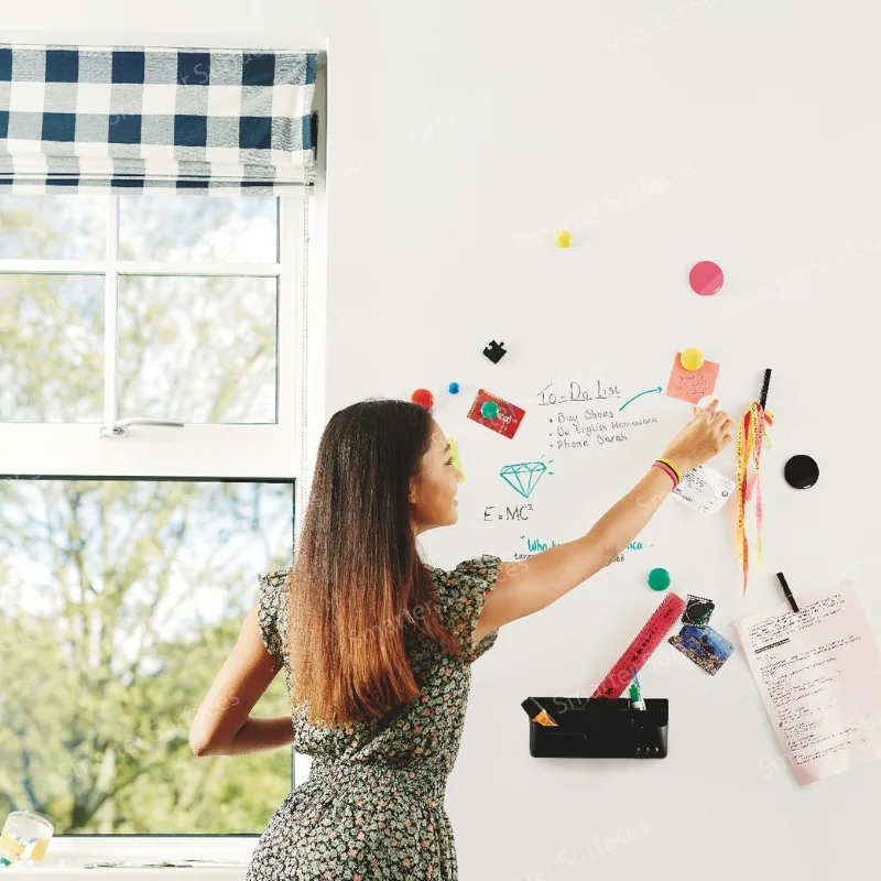 Woman writing on clear magnetic dry erase board with colorful magnets and notes attached, demonstrating transparent dry-erase functionality.