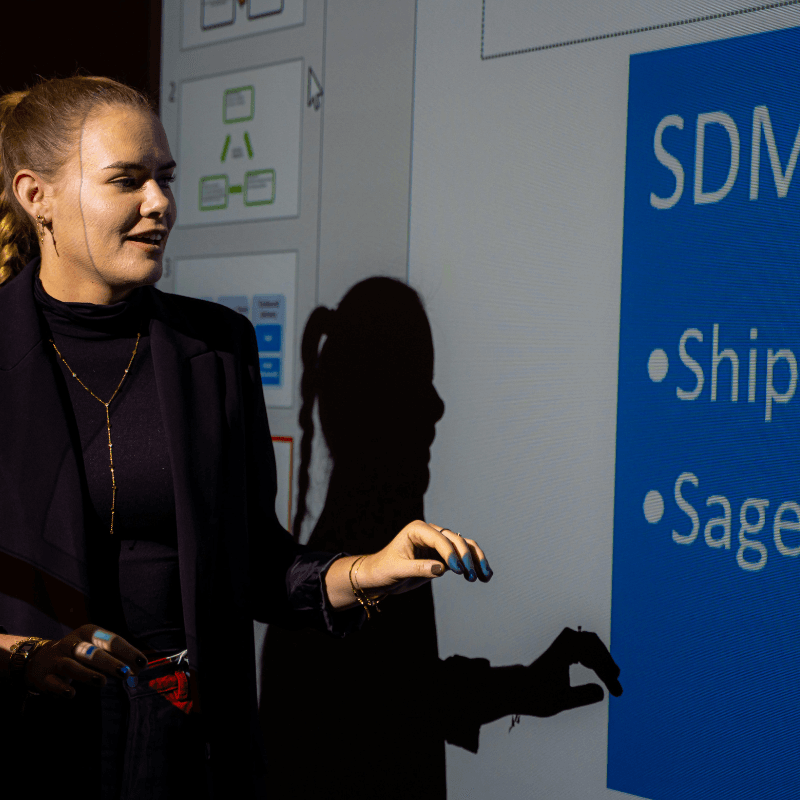 A woman giving a presentation using a clear projector screen