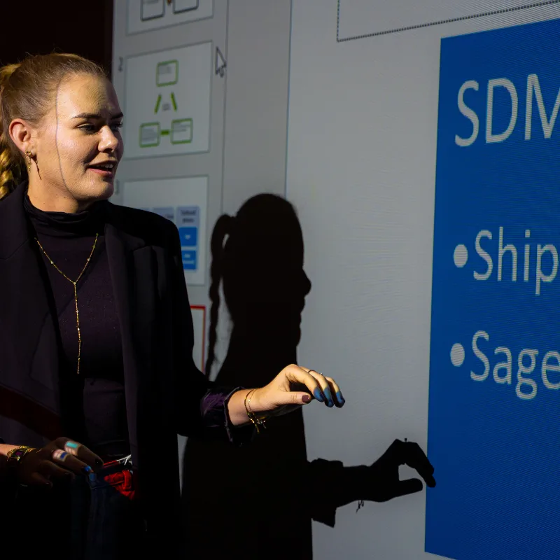 A woman giving a presentation using a clear projector screen