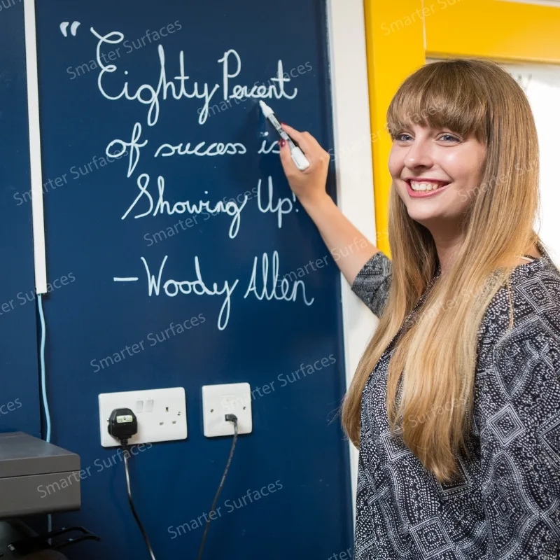 A woman writing a motivational quote on a whiteboard painted wall