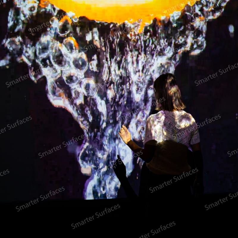 Person interacting with colorful projection on Black Projector Screen Paint