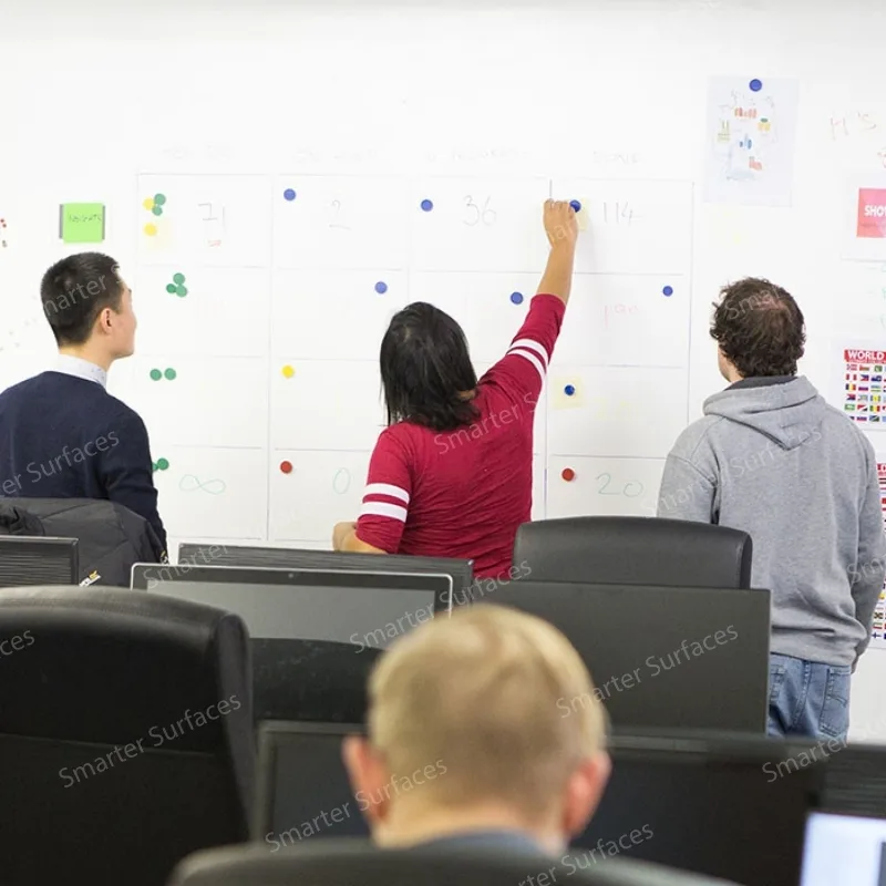 Team collaborating using white magnetic plaster wall with colorful sticky notes, magnets, and documents.