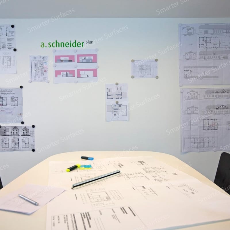 Architecture or design studio workspace with white magnetic whiteboard paint clear wall displaying building floor plans, architectural blueprints, and elevation drawings
