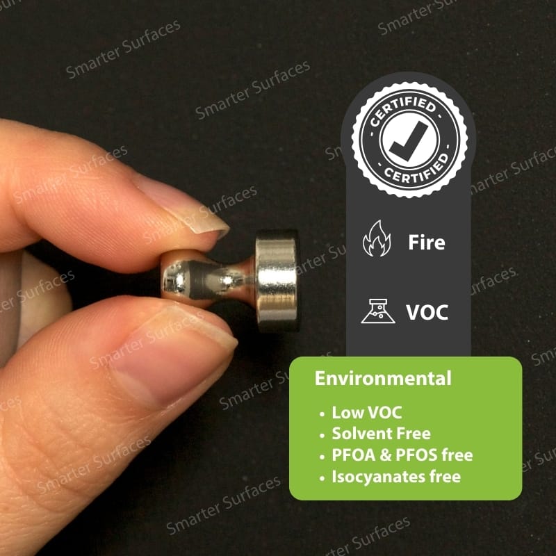 Hand holding a magnet on a certified Super Magnetic Paint surface showing environmental and safety certifications