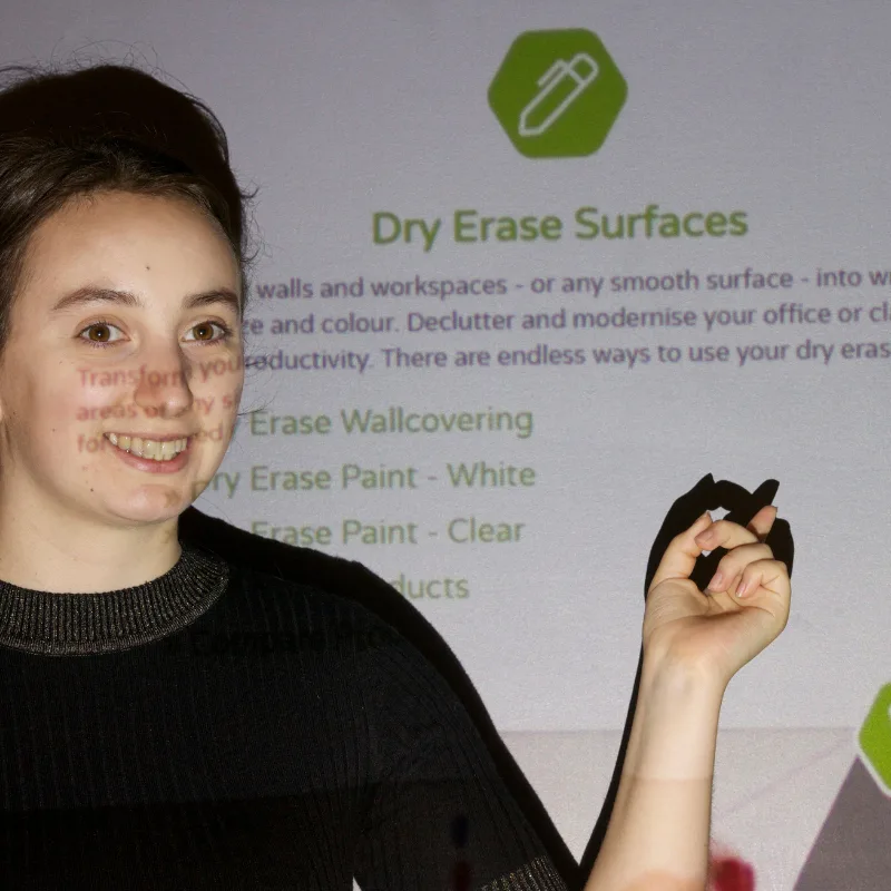 A woman pointing at text projected on a transparent projection surface