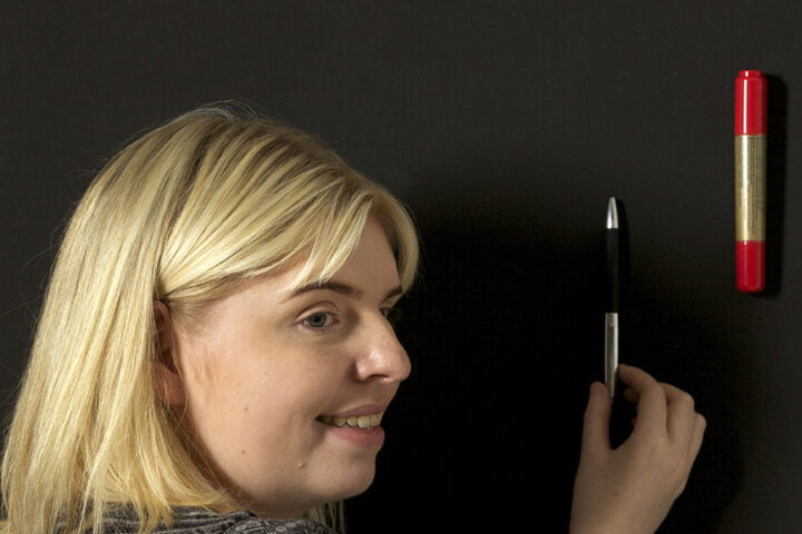 Woman sticking up items on super magnetic paint for walls
