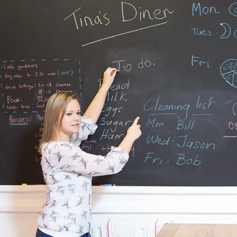 Woman writing to do list in cafe on chalkboard paint wall