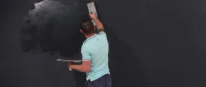 A man is applying magnetic chalkboard paint to a wall with a trowel