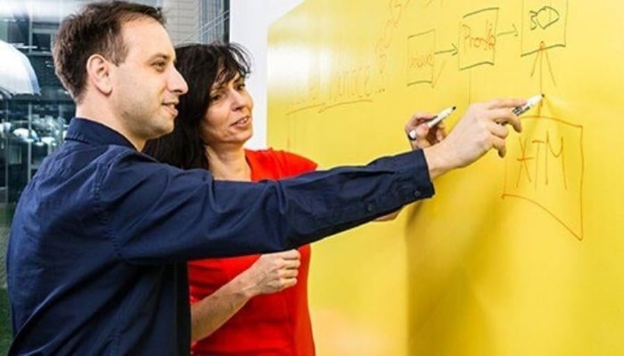 Man and women using yellow colored whiteboard walls