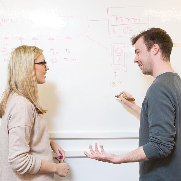 Man drawing on office whiteboard surface created with smart whiteboard wallpaper during meeting