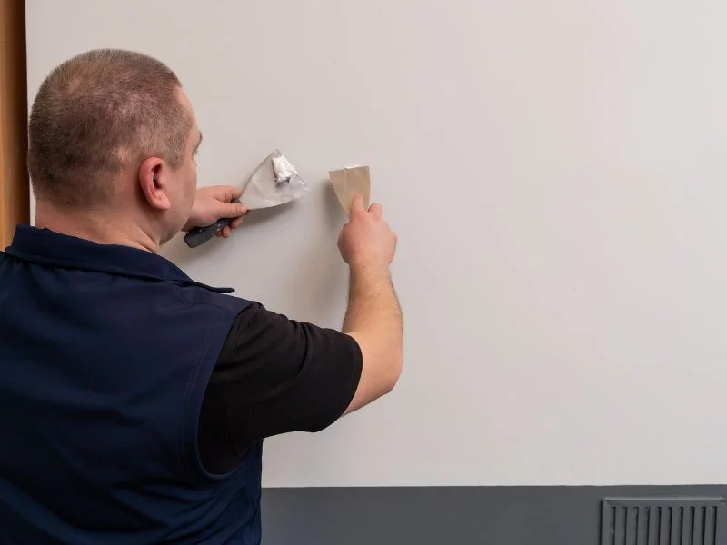 Step 5 Man preparing surface for applying magnetic gray paint by filling holes with decorators filler