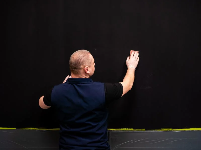 Step 10 - Man sanding surface after applying first coat of magnetic gray paint